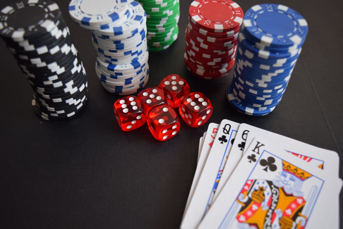 Chip kasino, dadu, dan kartu remi di atas meja hijau
