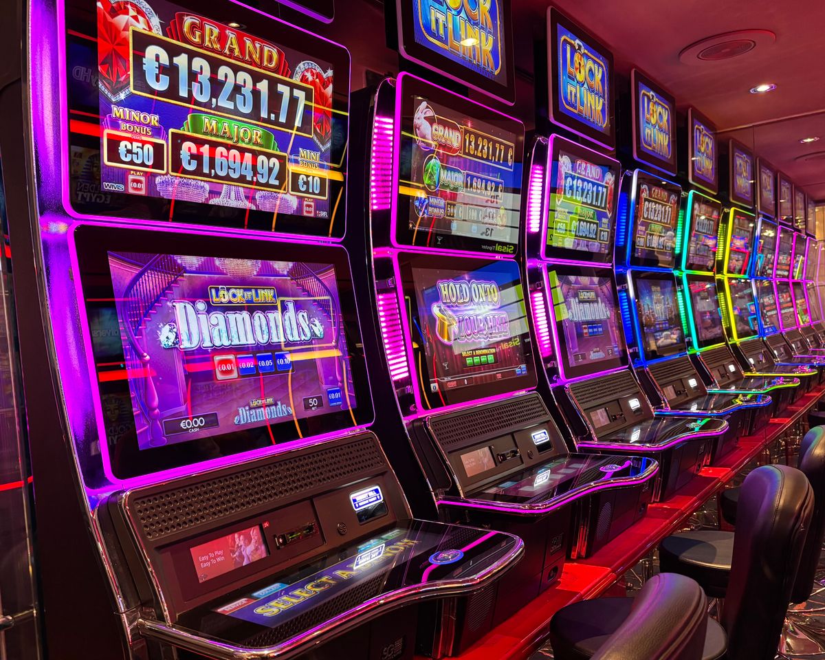 Deretan mesin slot kasino dengan layar warna-warni